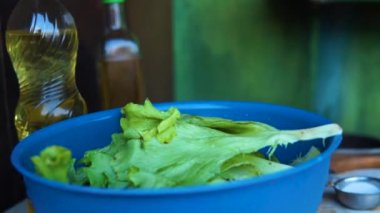 Mavi bir kasenin yakın çekimi, içinde marul yaprakları var..