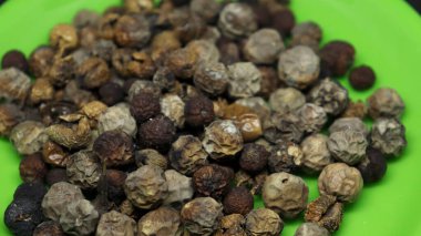 Güneşte kurutulmuş hindi üzümü yığını sarı bir tabakta siyah bir zemin üzerinde.