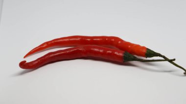 İki uzatılmış kırmızı ve turuncu kırmızı biber beyaz arka planda.