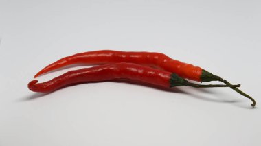 İki uzatılmış kırmızı ve turuncu kırmızı biber beyaz arka planda.