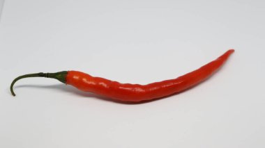 Beyaz arka planda uzatılmış turuncu yeşil biber var.