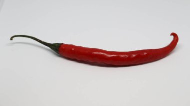 Beyaz arka planda uzatılmış kırmızı biber var.