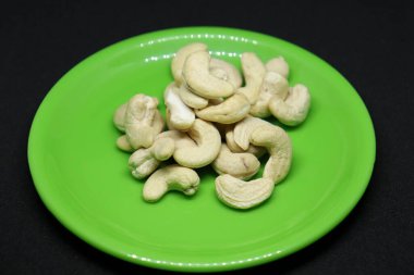 Ceviz yığını yeşil bir tabakta siyah bir arka planda.