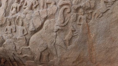 Taşa oyulmuş heykeller. Kaya arka planda yer alıyor.