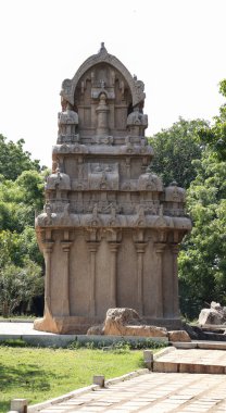 Yere taş oyulmuş bir tapınak. Ve içinde bir sürü heykel var. Doğal arka planda yer alıyor. Bir kenar görünüm.