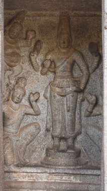 Taşa oyulmuş bir Hindu tanrısının heykeli. Kaya arka planda yer alıyor.