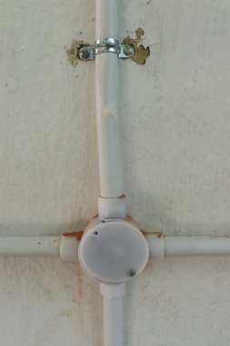 Duvarda plastik boru ve dört açılı boru var.