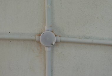 Duvarda plastik boru ve dört açılı boru var.