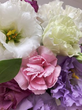 Bir buket çiçekli bir sepet. Güller ve kasımpatılar pembe arka planda bir sepette.