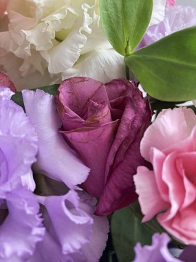 Bir buket çiçekli bir sepet. Güller ve kasımpatılar pembe arka planda bir sepette.