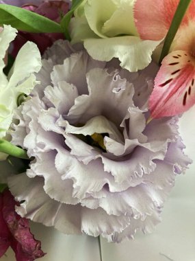 Bir buket çiçekli bir sepet. Güller ve kasımpatılar pembe arka planda bir sepette.