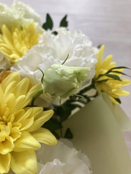 Bir buket çiçekli bir sepet. Güller ve kasımpatılar pembe arka planda bir sepette.