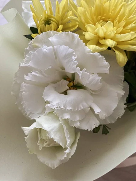 Bir buket çiçekli bir sepet. Güller ve kasımpatılar pembe arka planda bir sepette.