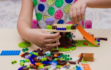Ulyanovsk, Rusya, Kasım 15, 2021: 5 yaşındaki bir çocuk Lego inşaatçı arkadaşlarının küçük renkli parçalarından ev topluyor. konsept