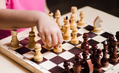 Küçük bir kız, 5 yaşında, bir dairede ahşap satranç oynuyor..