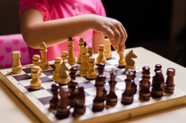 Küçük bir kız, 5 yaşında, bir dairede ahşap satranç oynuyor..