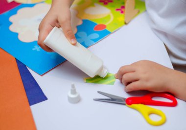 Çocuk hacimli bir uygulamayı kesiyor ve onu çizime yapıştırıyor - şablon. Bulanık, odaklanmış, seçici odaklanma. Boşluğu kopyala