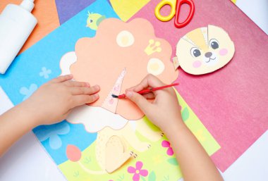 Çocuk hacimli bir uygulamayı kesiyor ve onu çizime yapıştırıyor - şablon. Bulanık, odaklanmış, seçici odaklanma. Boşluğu kopyala