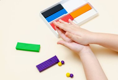 5 yaşındaki bir kız çocuğu plastikten figürleri bağımsız olarak şekillendiriyor..