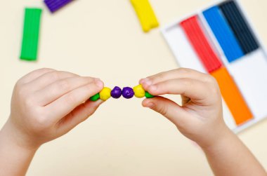 5 yaşındaki bir kız çocuğu plastikten figürleri bağımsız olarak şekillendiriyor..