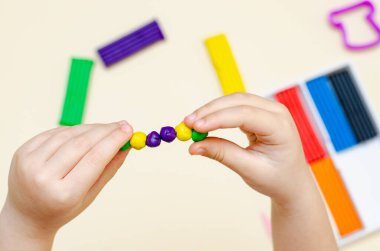 5 yaşındaki bir kız çocuğu plastikten figürleri bağımsız olarak şekillendiriyor.