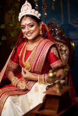 Portrait of beautiful bride in elegant wedding dress with bridal jewelry and bangle makeup with gorgeous saree studio indoor with heavy bokeh lighting. Sensuality and glamour. Portrait of beautiful adult bride in traditional bengali saree & Jewelry.