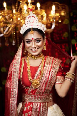 Portrait of beautiful bride in elegant wedding dress with bridal jewelry and bangle makeup with gorgeous saree studio indoor with heavy bokeh lighting. Sensuality and glamour. Portrait of beautiful adult bride in traditional bengali saree & Jewelry.
