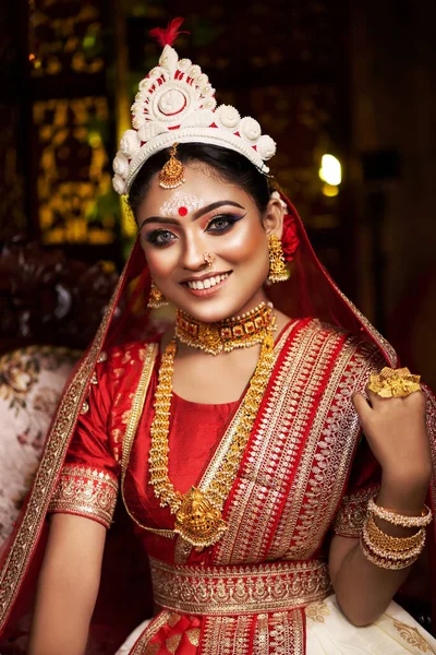 Portrait of beautiful bride in elegant wedding dress with bridal jewelry and bangle makeup with gorgeous saree studio indoor with heavy bokeh lighting. Sensuality and glamour. Portrait of beautiful adult bride in traditional bengali saree & Jewelry.