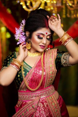 Sari ve altın takılar içinde güzel bir gelinin yakın plan portresi. Kapalı mekan fotoğrafçılığında muhteşem bir ifade. Eski Hint dekorasyonu olarak süslenmiş.. 