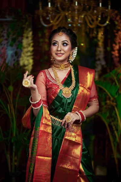Beautiful portrait of a south indian bride wearing green saree and jewelry. Pleasant expression.