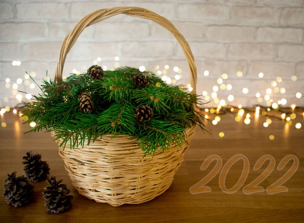 beautiful wicker basket with Christmas tree branches and pine cones, number 2022, creative tree on the eve of Christmas and Christmas holidays