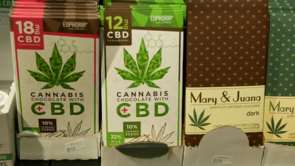 PRAGA, REPÚBLICA CHECA, 25 DE SEPTIEMBRE DE 2021: Tienda de chocolate de cannabis CBD en Praga, semillas de rick de cacao de cáñamo envasadas y oscuro en alivia el dolor, símbolo de la hoja, nueces de leche estante con azúcar — Vídeo de stock