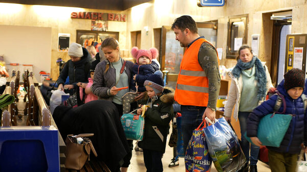 BOHUMIN, CZECH REPUBLIC, MARCH 17, 2022: Refugees Ukraine children family people Adra volunteer helps bags luggage, arriving train Bohumin central station relief, mother sitting bench baby, Russia war