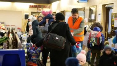 BOHUMIN, CZECH REPUBLIC, 17 Mart 2022: Mülteciler Ukraynalı çocuklar aile bireyleri Adra gönüllüleri valizlere yardım ediyor, Bohumin Merkez İstasyonu 'na giden tren yardım ediyor, anne bankta oturuyor, Rusya savaşı