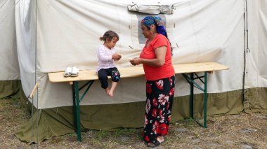 Göçmen mülteciler Ukrayna toplama kampı çingeneler aile çocukları bebek arabaları Roman büyükanneler ve torunlar Brno Ukrayna tren kampında omlet yiyorlar.