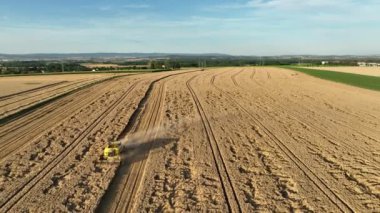Harvester combine drone aerial view during harvesting harvest tractor of cereals wheat cut crop Triticum aestivum field has-field, earth ground, landscape country village and river, quadcopter view