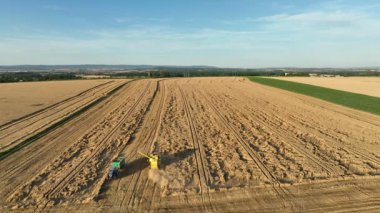 Harvester combine drone aerial view during harvesting harvest tractor of cereals wheat cut crop Triticum aestivum field has-field, earth ground, landscape country village and river, quadcopter view
