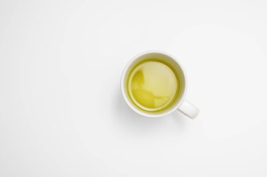 Ara veriyoruz: beyaz bir masa yüzeyinde büyük bir fincan yeşil ya da bitkisel çay. En küçük tablo görünümü ve kopyalama alanı.