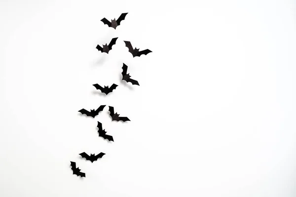 Halloween concept: A flock of black paper bats taking off on white background. Table top view, flat lay, copy space.
