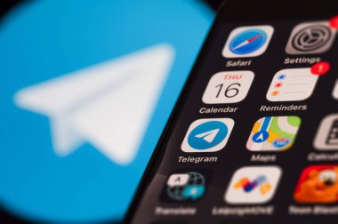 Telegram anlık mesaj servisi konsepti. Çeşitli uygulama simgelerini gösteren akıllı telefon ekranı. Arka planda bulanık bir Telegram logosu.