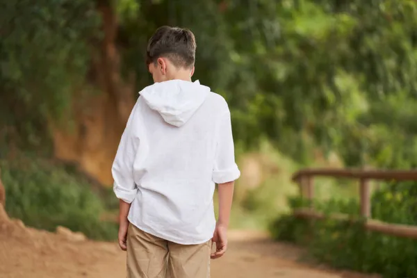 young boy with his back turned walking in the field