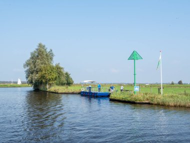 GROUW, NETHERLANDS - SEP 24, 2017: Bisikletli yaşlı çift Grou, Friesland yakınlarındaki kanalı geçtikten sonra Snoeckbear feribotundan ayrılıyorlar
