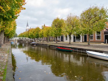 LOTEN, NETHERLANDS - OCT 2, 2017: kanal üzerindeki yaya köprüsü ve Sleat, Friesland kentindeki Heerenwal rıhtımında evler