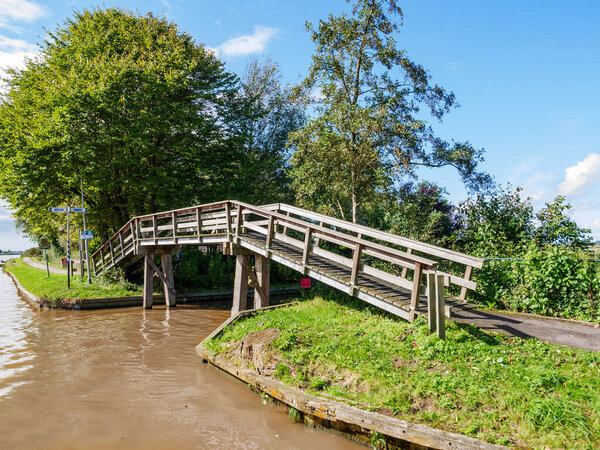 Wooden footbridge for bicycles and pedestrians by Dokkumer Ee in town of Bartlehiem, Friesland, Netherlands