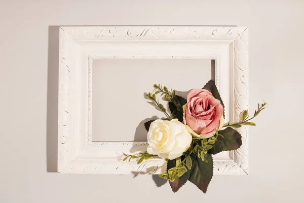 White and pink roses in vintage painting frame on light background. Spring or summer aesthetic creative idea. Minimal flat lay.