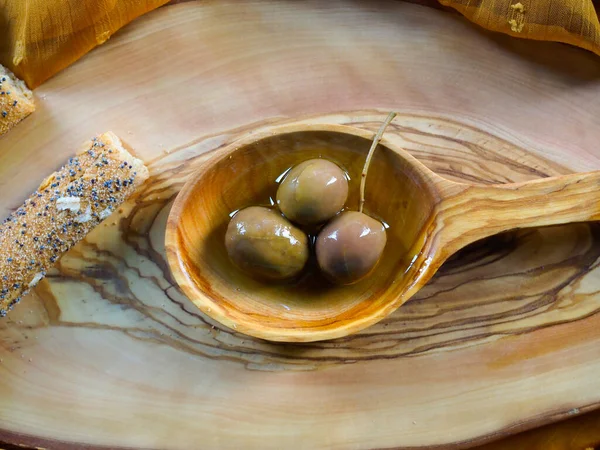 Olive wood wooden spoon, with some olives and olive oil inside