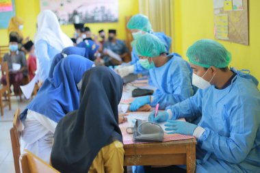 Pasuruan, Endonezya, 26 Ekim 2021. Doktor, İslam yatılı okulundaki öğrencilere aşı enjekte ediyor.