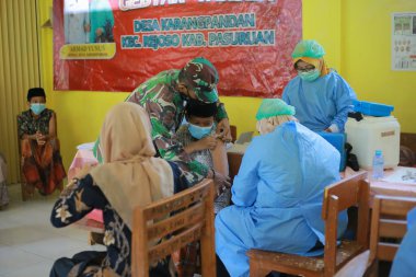Pasuruan, Endonezya, 26 Ekim 2021. Doktor, İslam yatılı okulundaki öğrencilere aşı enjekte ediyor.