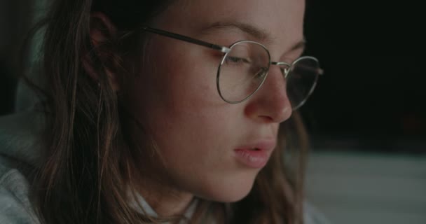 Крупним планом на окулярах молодої жінки працюють на ноутбуці — стокове відео