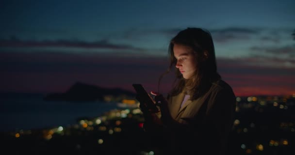 Junge Frau schaut im Sonnenuntergang aufs Handy